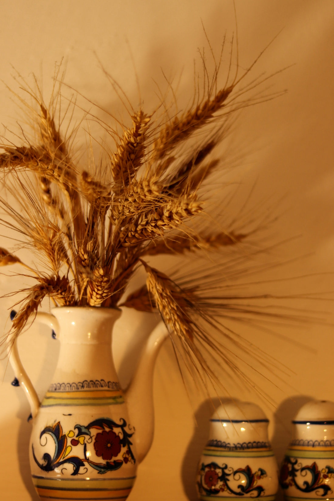 a white vase with a bunch of wheat in it