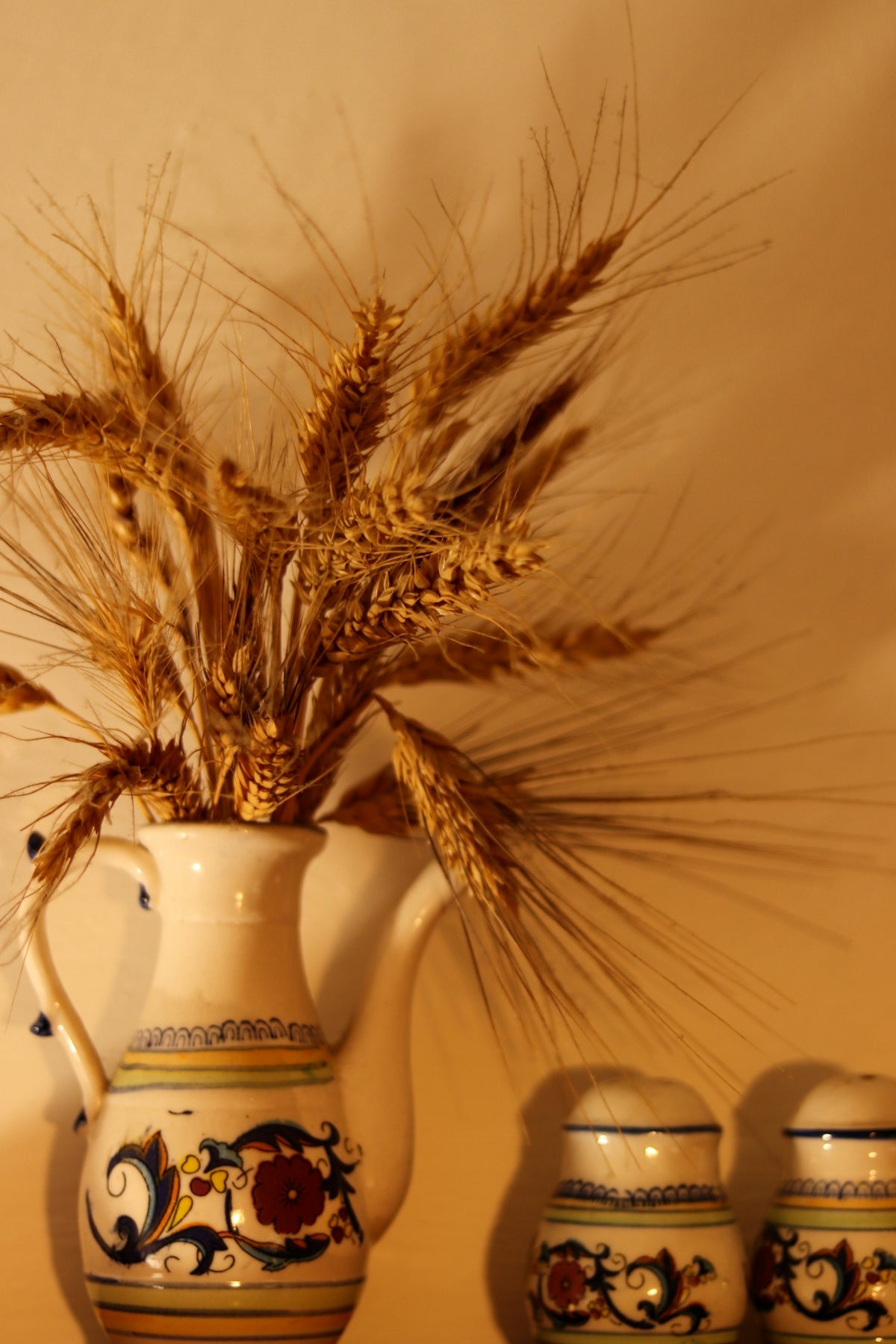 a white vase with a bunch of wheat in it