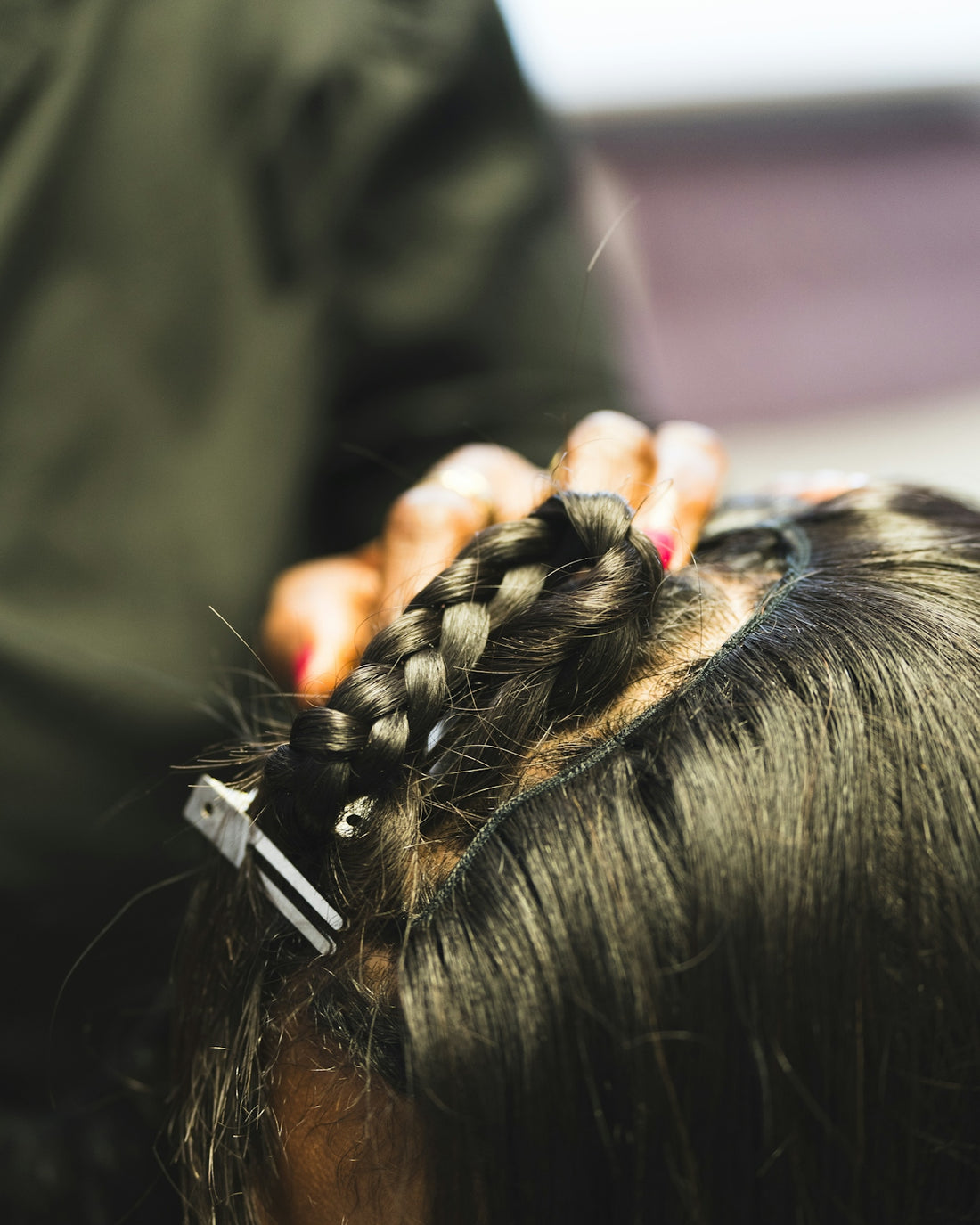Stylist braiding dark hair for a client.